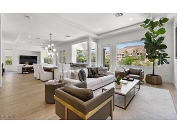 Bright, open living room with modern furnishings, hardwood floors, and mountain views from the large windows at 2797 Turtle Head Peak Dr, Las Vegas, NV 89135