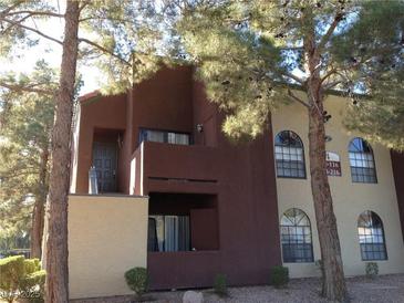 Inviting two-story condo building with a combination of light and dark stucco and mature trees at 4050 Pacific Harbors Dr # 214, Las Vegas, NV 89121