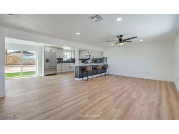 Open-concept living room flows into kitchen featuring a large island with bar seating and stainless steel appliances at 5200 Blanton Dr, Las Vegas, NV 89122