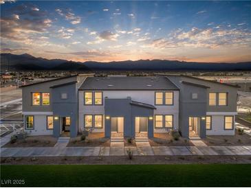 Inviting two-story townhome showcasing desert landscaping and a serene mountain backdrop at sunset at 6197 Hibiscus Garden St # 177, North Las Vegas, NV 89081