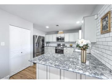Charming kitchen with white cabinets, stainless steel appliances, and elegant countertops at 6920 Singing Dunes Ln, Las Vegas, NV 89145