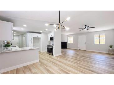 Bright living room featuring an open floor plan with modern lighting and sleek wood-look floors at 744 Hubbard St, Las Vegas, NV 89110