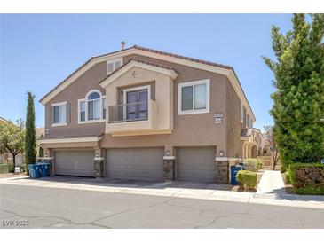 Inviting townhome featuring attached garages, tan stucco, and a charming balcony with a metal railing at 8639 Horizon Wind Ave # 102, Las Vegas, NV 89178