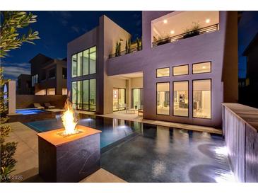 Inviting backyard pool with a fire pit, water feature, and modern home exterior at twilight at 10752 Patina Hills Ct, Las Vegas, NV 89135