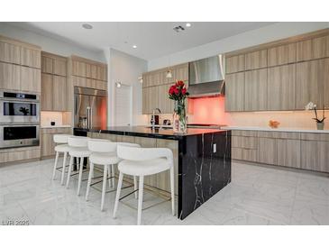 Modern kitchen with a large black marble island, stainless steel appliances, and stylish seating at 10752 Patina Hills Ct, Las Vegas, NV 89135