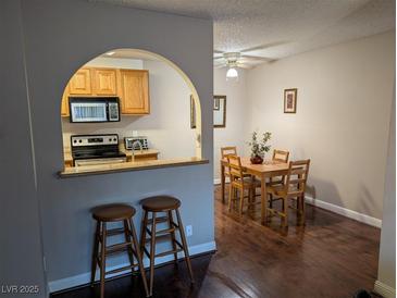 Bright dining area with dark wood floors adjacent to an open kitchen featuring stainless steel appliances at 1515 E Reno Ave # C207, Las Vegas, NV 89119