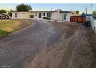 A single story home with a dirt driveway, a well-manicured lawn, and a brown wooden fence at 5617 Alfred Dr, Las Vegas, NV 89108