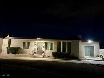 Night view of a single-story home featuring a decorative front door and well-maintained landscaping at 5617 Alfred Dr, Las Vegas, NV 89108