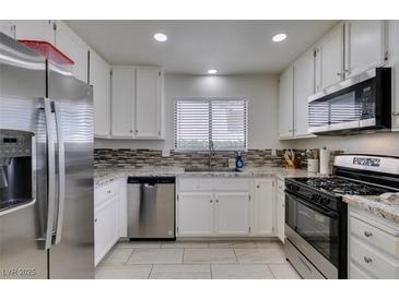 Well-lit kitchen with stainless steel appliances, granite countertops, and mosaic tile backsplash at 368 Umbria Way, Henderson, NV 89014