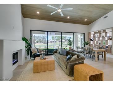 Bright living room with fireplace, modern decor, and large windows overlooking a golf course at 9425 Villa Ridge Dr, Las Vegas, NV 89134
