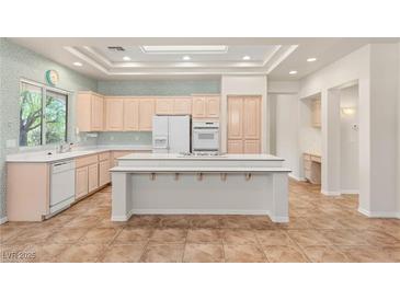Bright kitchen features tile flooring, an island with seating, modern appliances, and recessed lighting at 10548 Findlay Ave, Las Vegas, NV 89134