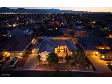 Stunning aerial view of a beautiful home, showcasing a well-manicured yard and neighborhood lights at dusk at 8149 Villa De La Playa St, Las Vegas, NV 89131