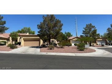 Inviting single story home boasts a well-manicured front yard and a two-car garage at 9816 Villa Ridge Dr, Las Vegas, NV 89134