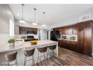 Modern kitchen with dark wood cabinets, white countertops, a kitchen island with barstools and stainless steel appliances at 209 Camino Vista St, Henderson, NV 89012