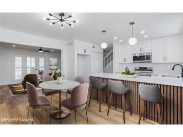 Bright kitchen and dining area boasts white cabinets, an island, and hardwood floors at 572 Tam O Shanter, Las Vegas, NV 89109