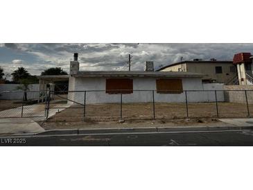 Exterior shot of a single-story home behind a chain link fence on an overcast day at 2645 Cedar Ave, Las Vegas, NV 89101