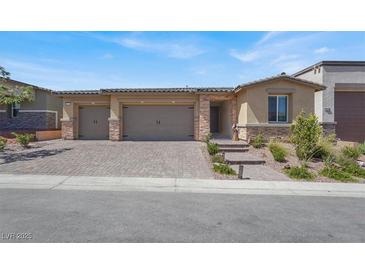 Charming home showcasing a three-car garage and well-maintained front yard with lush landscaping and beautiful hardscape at 10904 Ellis Pointe Ave, Las Vegas, NV 89166