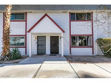 Two-story townhome featuring two front doors, white walls with red trim, and desert landscaping at 225 Pecos Way, Las Vegas, NV 89121