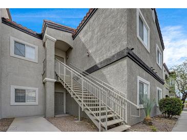 Condo exterior with stucco, gray paint, tile roof, staircase, and desert landscaping at 6160 Rumrill St # 202, Las Vegas, NV 89113