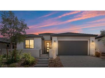 Charming home with a gray exterior, black garage door and desert landscaping at 64 Lake Oasis St, Henderson, NV 89011
