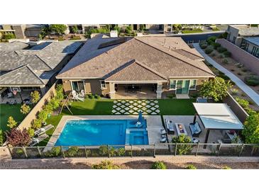 Stunning aerial view of backyard featuring a pool, spa, covered patio, lounge area, and lush landscaping at 9972 Terrastone Dr, Las Vegas, NV 89148