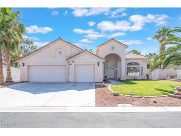 Charming home featuring a three-car garage, arched entryway, manicured lawn, and mature palm trees at 4116 Villa Flora St, Las Vegas, NV 89130