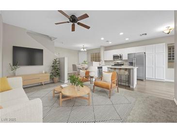 Cozy living room with modern decor, featuring an open floor plan flowing into a bright kitchen and dining area at 6460 Raven Hall St, North Las Vegas, NV 89084