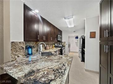Well lit kitchen with stainless steel sink, granite countertop, and dark wood cabinets at 7952 Lonette Ave, Las Vegas, NV 89147