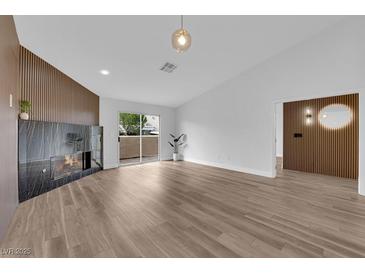 Bright living room featuring a modern fireplace, wood-look floors, and sliding glass doors to bring the outside in at 9412 Mount Cherie Ave # 102, Las Vegas, NV 89129