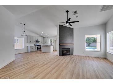 Open-concept living room featuring light wood floors, a modern fireplace, and bright white walls at 6126 Bedrock Ct, North Las Vegas, NV 89031