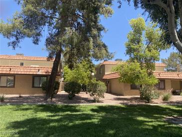 Charming condo featuring a red tile roof, complemented by mature trees and a lush green lawn at 1843 Mimosa Ct, Henderson, NV 89014