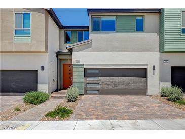 Modern two-story home with a gray garage door, a brick driveway, and colorful front door at 3358 Via Strada St, Henderson, NV 89044