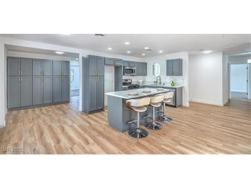 Bright kitchen features gray cabinets, island with seating, stainless appliances, and hardwood-style flooring at 6517 Villa Mesa Dr, Las Vegas, NV 89107