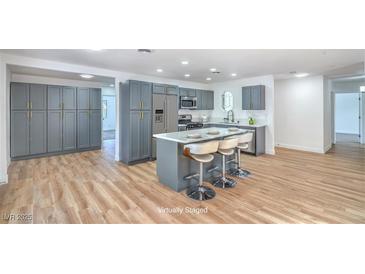 Modern kitchen with gray cabinets, stainless steel appliances, and a sleek island with bar seating at 6517 Villa Mesa Dr, Las Vegas, NV 89107