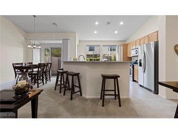 Open-concept kitchen features bar seating, stainless steel appliances, and lots of natural light at 9256 Blue Flax Pl, Las Vegas, NV 89148