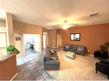 Open-concept living room features neutral paint, ceiling fan, and gray sofas at 10717 Grand Cypress Ave, Las Vegas, NV 89134