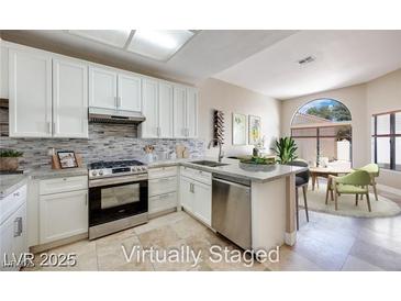 Modern kitchen featuring white cabinets, stainless steel appliances, and a stylish backsplash at 2723 Seabridge Dr, Las Vegas, NV 89121