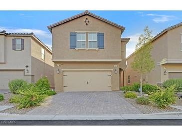 Charming two-story home featuring a two-car garage, brick driveway, and manicured landscaping at 9327 Ettrick Ct, Las Vegas, NV 89178