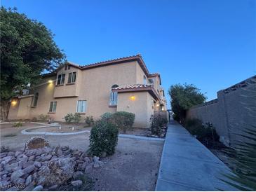 Inviting two-story townhouse with desert landscaping, warm lighting, and a private walkway at 558 Roxella Ln # D, Las Vegas, NV 89110
