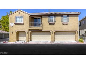 Three-unit tan townhome featuring individual garages and a small balcony on the second level at 3905 Sweet Pine St # 102, Las Vegas, NV 89108