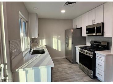 Modern kitchen features white cabinets, stainless steel appliances, and light countertops at 7144 Forest Vista St, Las Vegas, NV 89147
