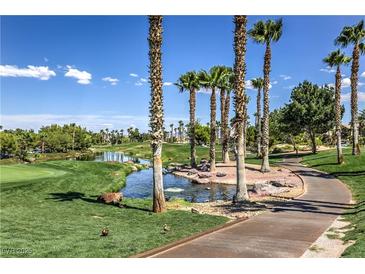 Scenic golf course view featuring lush greenery, palm trees, and a tranquil water feature on a sunny day at 261 Fairway Woods Dr, Las Vegas, NV 89148