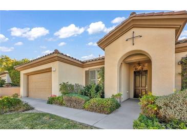 Inviting single-story home featuring a Mediterranean-style facade, arched entrance and manicured landscaping at 37 Stonemark Dr, Henderson, NV 89052