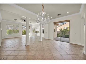 Bright living room boasts an ornate chandelier, tile floors, and sliding glass doors to the backyard at 37 Stonemark Dr, Henderson, NV 89052