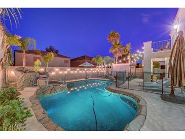 Backyard pool featuring rock waterfall, decorative lighting, and mature landscaping at 1717 Jake Andrew Ave, North Las Vegas, NV 89086