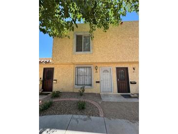 Townhouse exterior featuring tan stucco, security doors, and landscaped front yard with decorative rock at 453 Las Casitas Way, Las Vegas, NV 89121