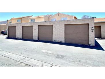 This image shows multiple garages with tan doors and textured walls under a blue sky at 5215 Gray Ln, Las Vegas, NV 89119