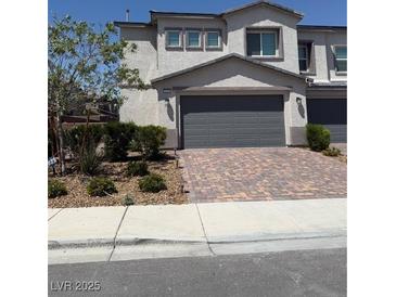 Two-story home with a brick driveway, a two-car garage, and well-maintained landscaping in front at 1618 Dakota Group Ave, North Las Vegas, NV 89084
