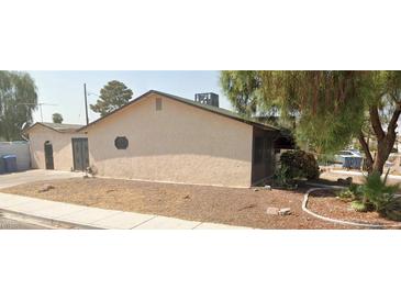 Side view of a modest stucco home with a low-pitched roof, desert landscaping, and mature trees at 3114 Scarlet Oak Ave, Las Vegas, NV 89104