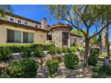 Stunning exterior of home with stone turret, well-manicured landscaping, and mature tree at 8010 Palm Cove Ct, Las Vegas, NV 89129